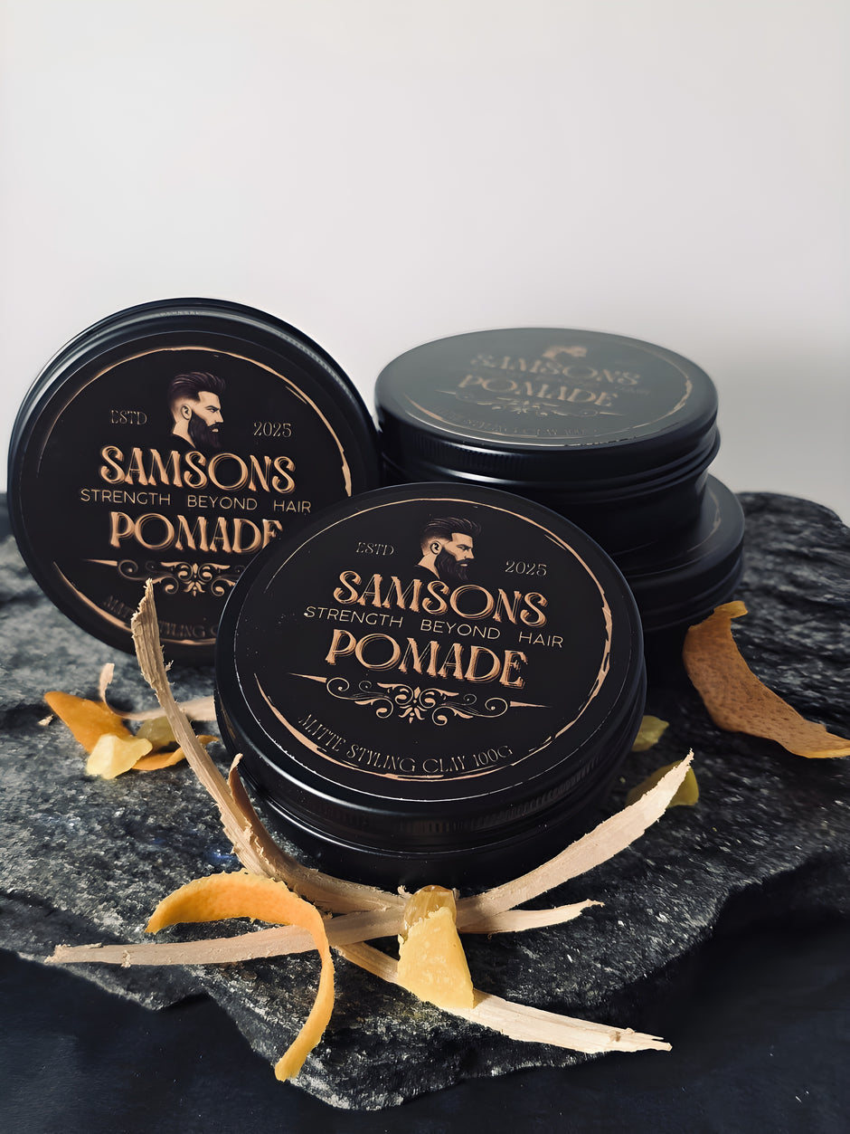 Three jars of Samson's Pomade on a dark surface with decorative elements. orange, cedar wood, frankincense