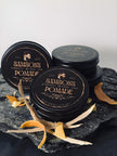 Three jars of Samson's Pomade on a dark surface with decorative elements. orange, cedar wood, frankincense